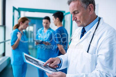 Doctor standing in corridor examining x-ray