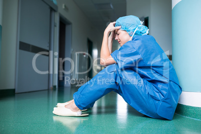 Sad surgeon sitting on floor in corridor