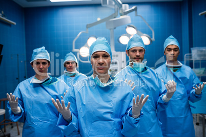Portrait of surgeons standing with hands raised in operation roo