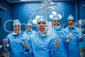 Portrait of surgeons standing with hands raised in operation roo