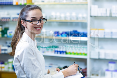 Pharmacist writing on clipboard in pharmacy