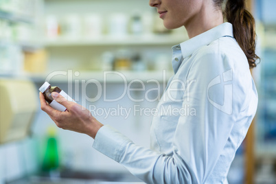 Pharmacist checking a bottle of drug in pharmacy