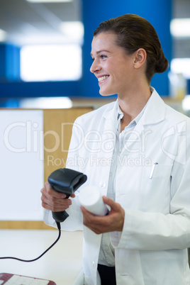 Smiling pharmacist using barcode scanner on medicine bottle