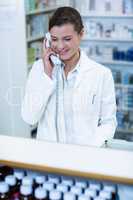 Pharmacist standing at counter and talking on phone