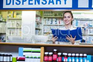 Pharmacist looking in clipboard at counter in pharmacy