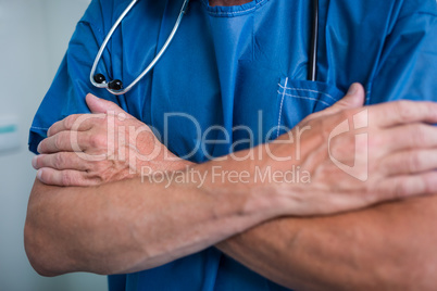 Mid section of surgeon standing with arms cross