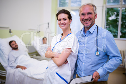 Smiling doctor and nurse standing in ward