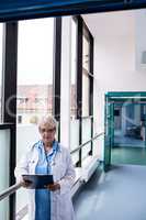 Doctor standing in corridor looking at clipboard