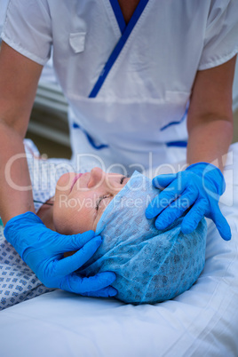 Nurse putting a surgical cap to patient
