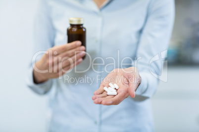 Pharmacist holding a medicine bottle and pills in pharmacy