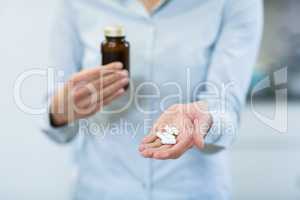 Pharmacist holding a medicine bottle and pills in pharmacy