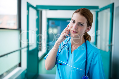 Portrait of surgeon talking on mobile phone in corridor Portrait of surgeon talking on mobile phone in corridor