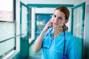 Portrait of surgeon talking on mobile phone in corridor
