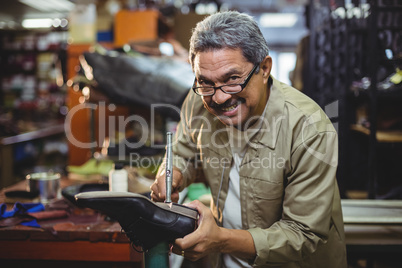 Portrait of smiling shoemaker hammering on a shoe