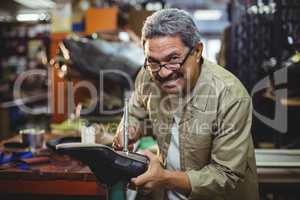 Portrait of smiling shoemaker hammering on a shoe