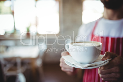 Mid-section male baker holding a cup of coffee