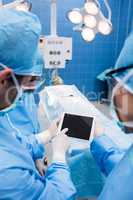Surgeons using digital tablet and patient lying on operation bed