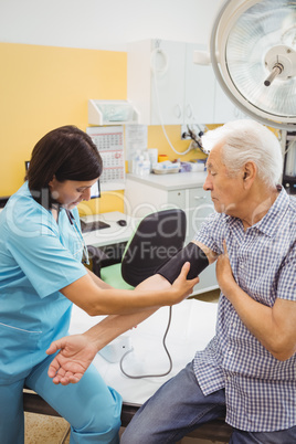 Female doctor checking blood pressure of patient