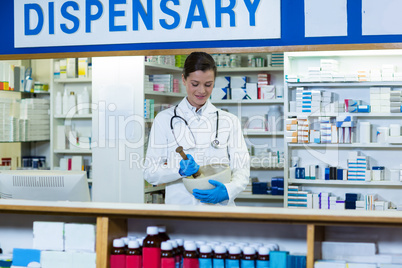 Pharmacist grinding medicine in mortal and pestle at counter