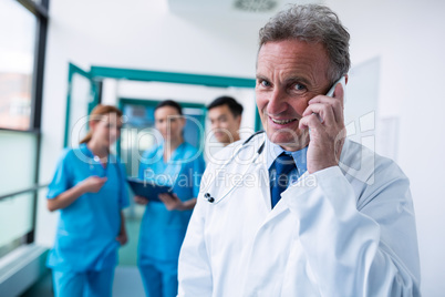 Portrait of smiling doctor talking on mobile phone in corridor