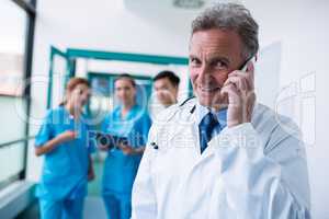 Portrait of smiling doctor talking on mobile phone in corridor