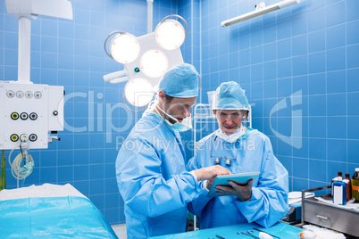 Surgeons discussing over digital tablet in operation room