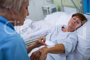 Nurse attaching iv drip on patients hand