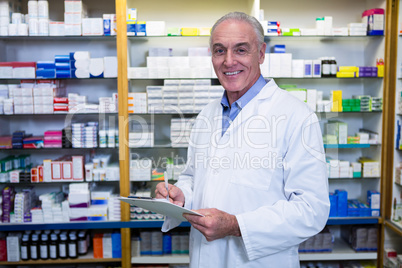 Pharmacist writing on clipboard in pharmacy