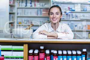 Smiling pharmacist sitting at counter in pharmacy