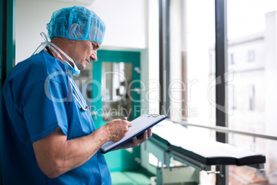 Surgeon writing on clipboard in corridor Surgeon writing on clipboard in corridor