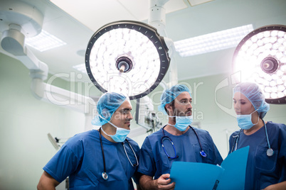 Surgeons discussing patient records in operation room