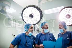 Surgeons discussing patient records in operation room