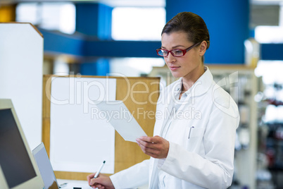 Pharmacist looking at prescription and writing on book