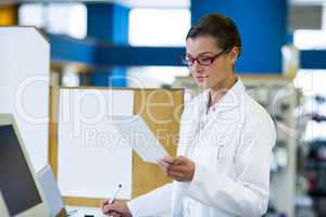 Pharmacist looking at prescription and writing on book