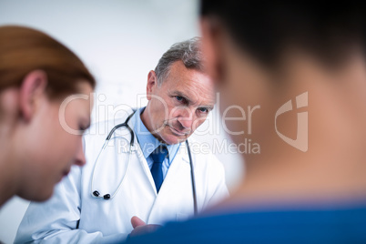Thoughtful doctor standing with surgeons in corridor