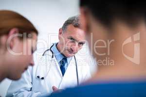 Thoughtful doctor standing with surgeons in corridor