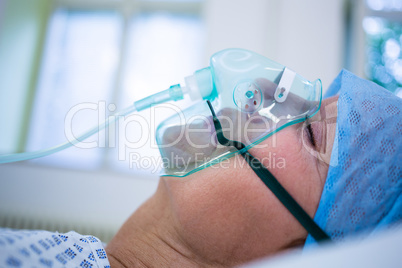 Patient wearing oxygen mask lying on hospital bed