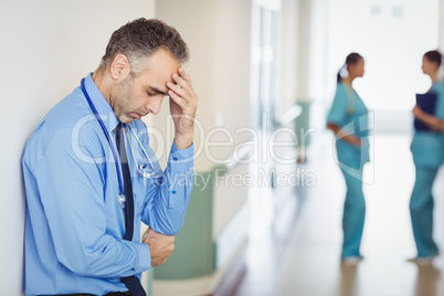 Sad doctor leaning against the wall