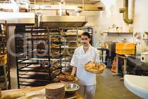 Female baker holding basket of sweet foods