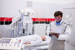 Doctor using digital tablet and patient lying on x ray machine