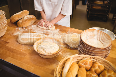 Mid-section of female baker kneading a dough