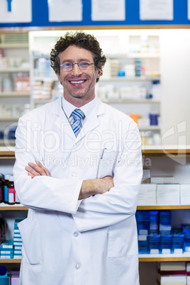 Pharmacist standing with arms crossed in pharmacy