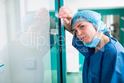 Portrait of sad surgeon leaning against the glass door
