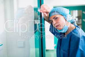 Portrait of sad surgeon leaning against the glass door