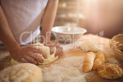 Mid-section of baker kneading a dough