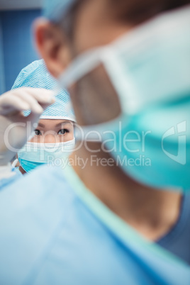 Close-up of nurse helping a surgeon in tying surgical mask