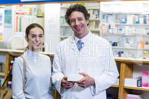 Smiling customer and pharmacist holding drug box in pharmacy