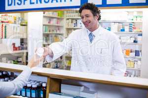 Pharmacist giving pill bottle to customer