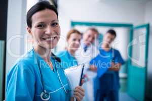 Portrait of smiling surgeon holding a clipboard in corridor