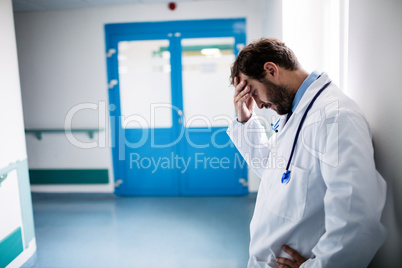 Sad doctor leaning against the wall